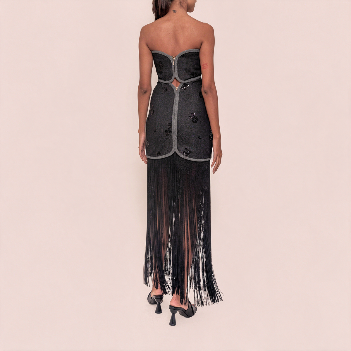 Back view of strapless black denim-look maxi dress with fringe hem and seamed panels